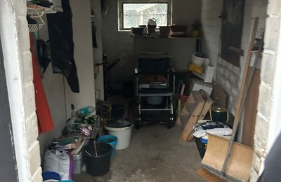 Garagenentrümpelung Hessen, chaotische Garage mit Eimern, Werkzeug und alten Möbeln wird fachgerecht geräumt