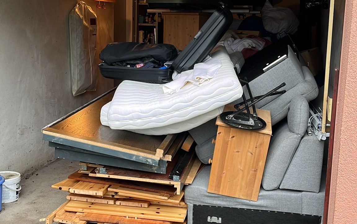 Garagenentrümpelung Hessen, vollgepackte Garage mit Sofa, Matratze, Koffern und Möbeln vor der Räumung