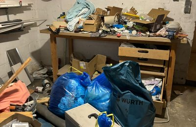 Kellerwerkstatt Entrümpelung Hessen, chaotischer Werkstattkeller mit Werkzeug, Müllsäcken und Gerümpel wird fachgerecht ausgeräumt