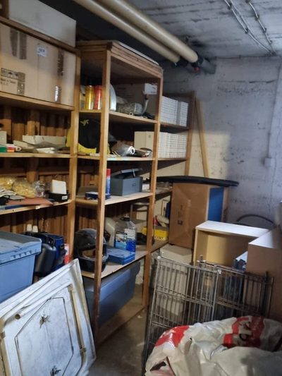 Vorher: vollgestellter Kellerraum mit Regalen und Gerümpel vor der Kellerentrümpelung in Hofheim