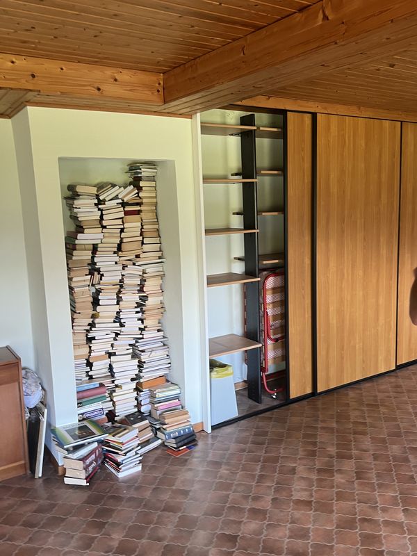 Vorher: Wohnraum mit vollen Bücherstapeln in der Wandnische vor der Entrümpelung in Königstein