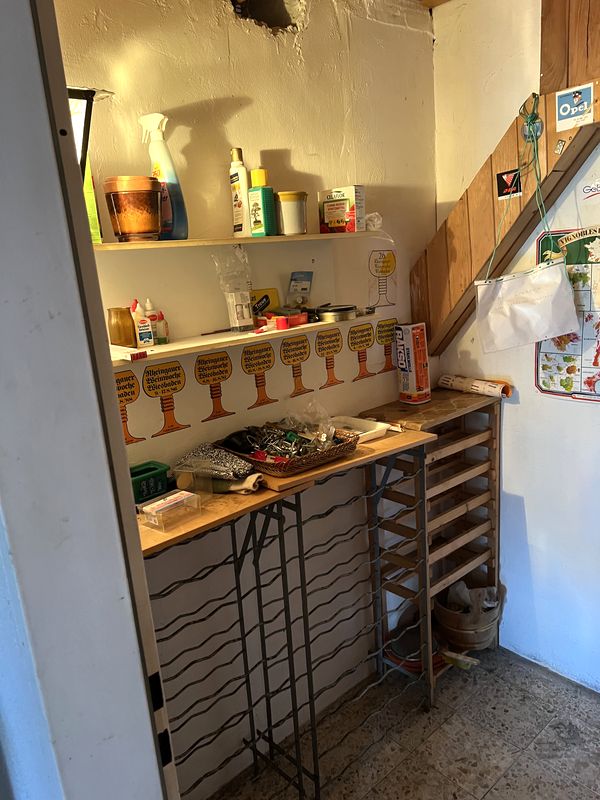 Vorher: vollgestellter Kellerraum mit Regalen und Weinregal vor der Kellerentrümpelung in Flörsheim
